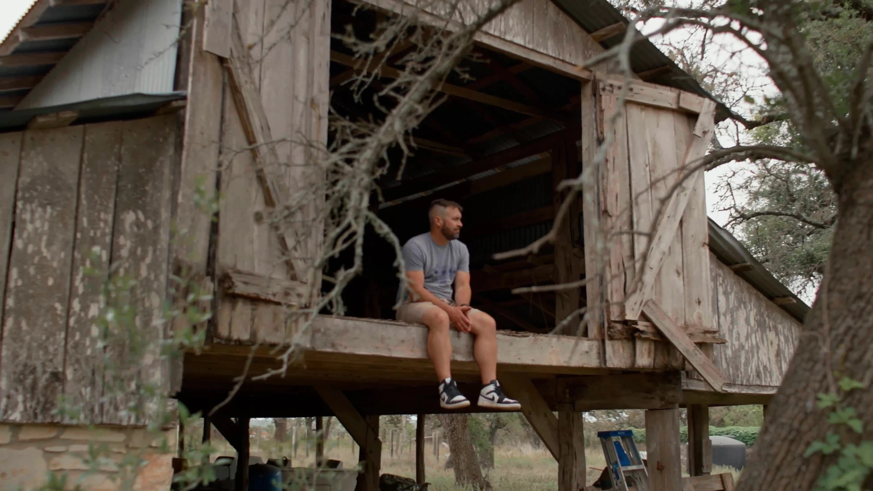A person sitting in the doorway of a raised wooden structure.
