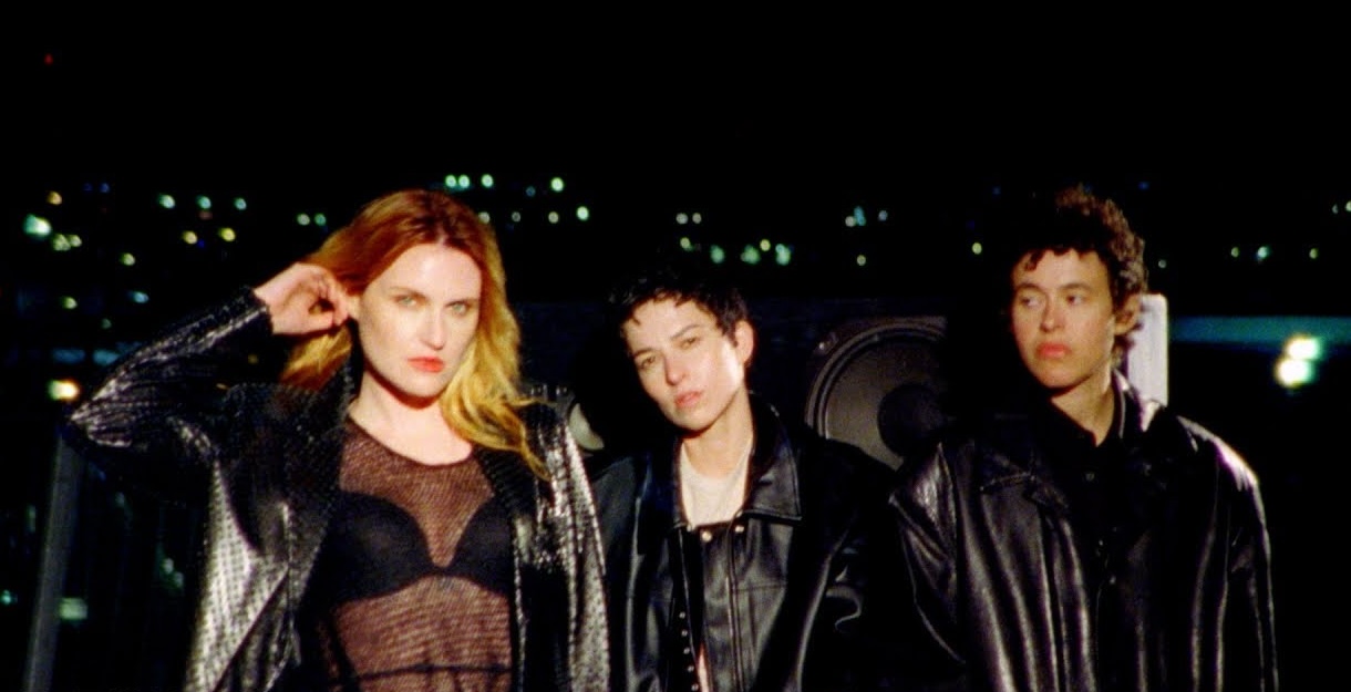 MUNA standing together in black jackets at night.