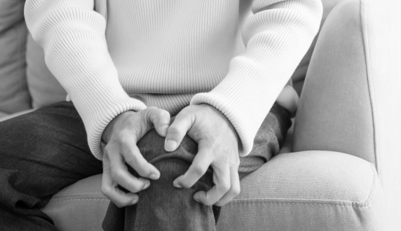 Older person seated with hands resting on their knee