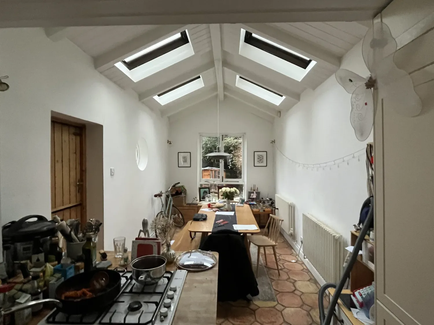 The kitchen before the works, under a pitched timber roof with four small skylights and hexagonal terracotta floor tiles