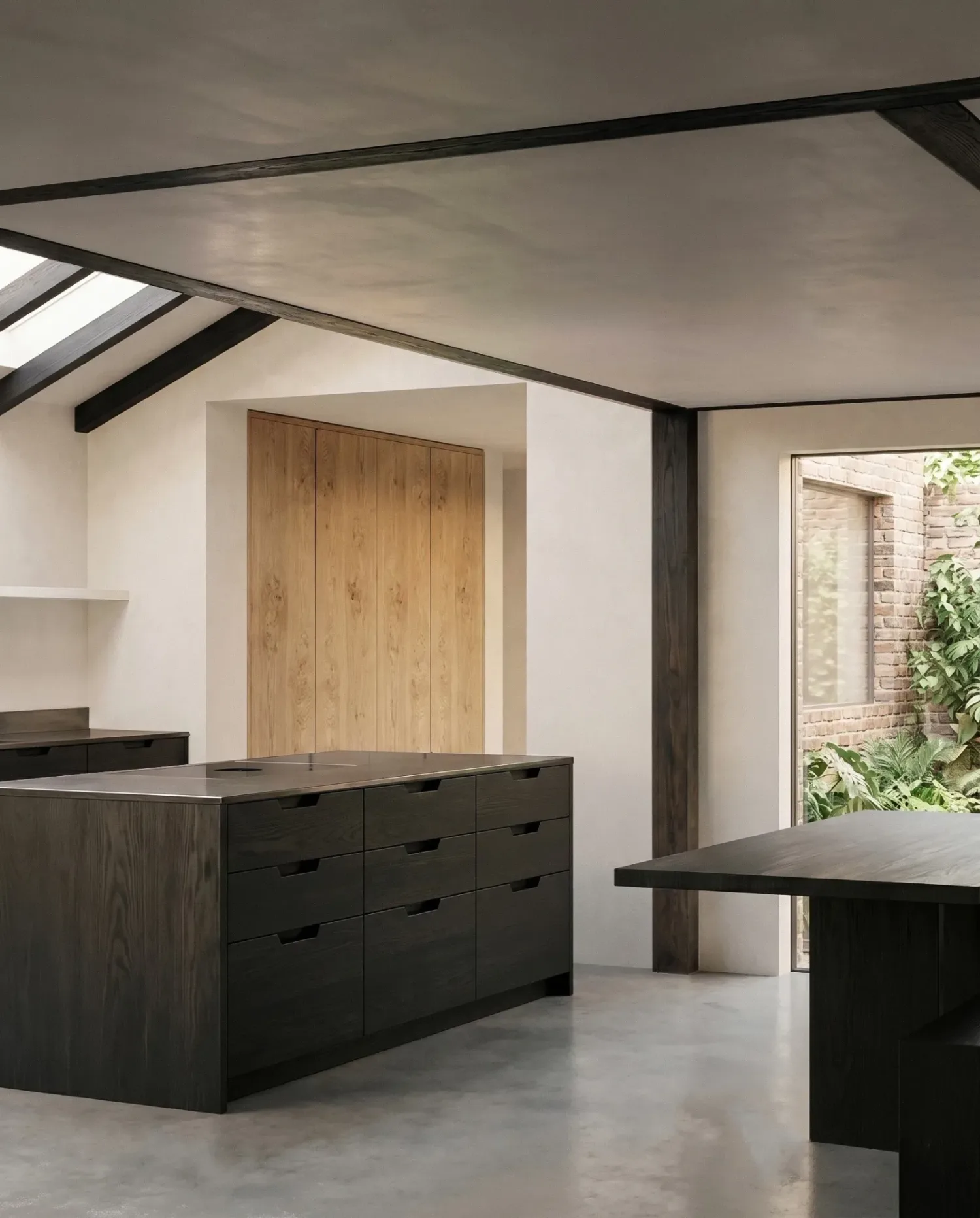 Interior view of the kitchen with exposed timber roof beams running across both the old and the new roof, all painted the same dark tone