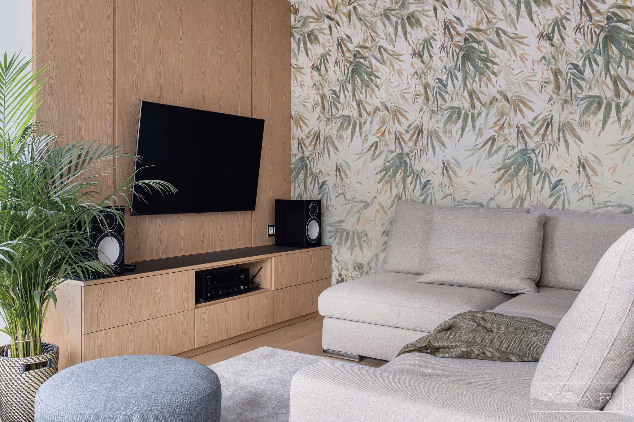 Salon z jasną sofą, drewnianą zabudową i dekoracyjną tapetą w Apartamencie Oliwa – ASAR PROJEKT