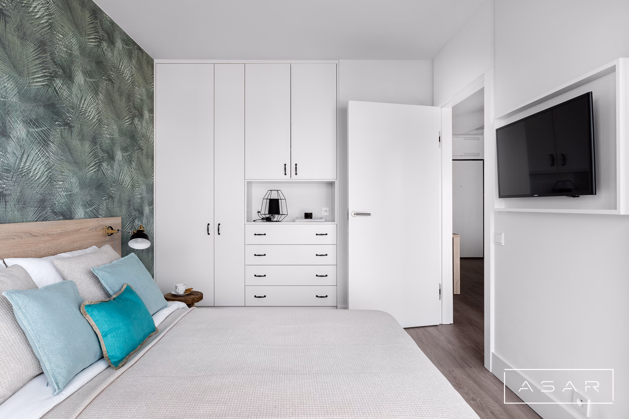 ASAR PROJEKT – sypialnia apartamentu z białymi meblami, drewnianym zagłówkiem i zieloną tapetą