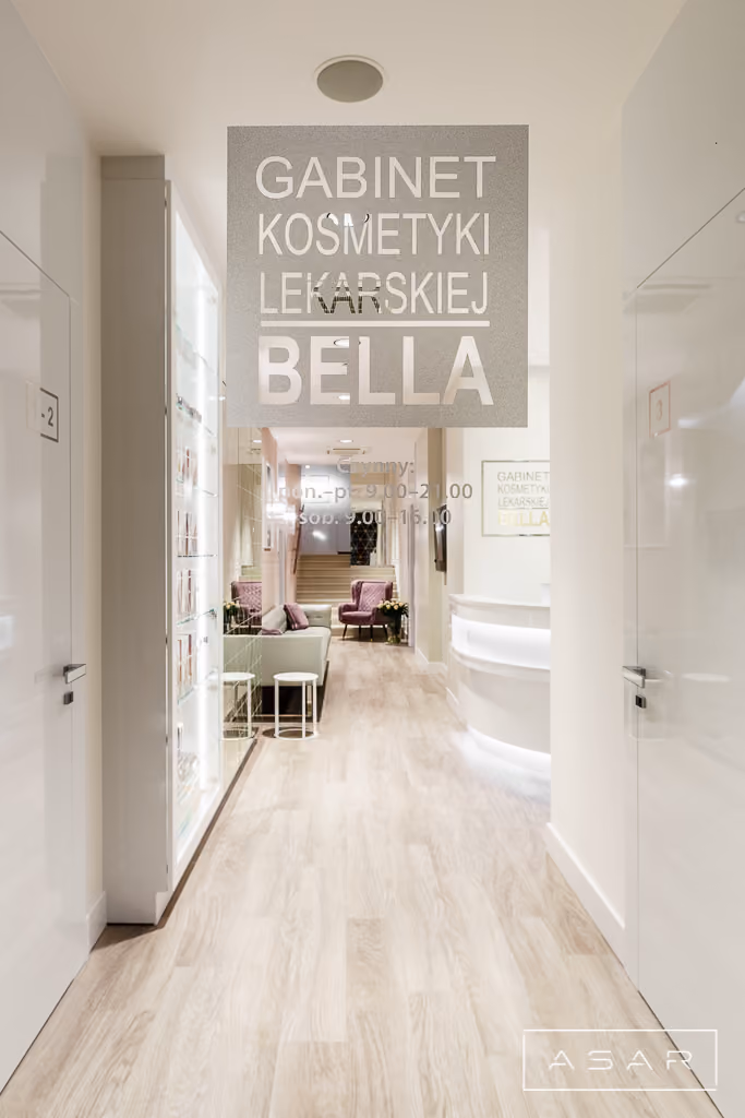 Detal wnętrza Kliniki Bella z jasną zabudową, dekoracyjną grafiką i pastelowym wykończeniem ściany – ASAR Projekt