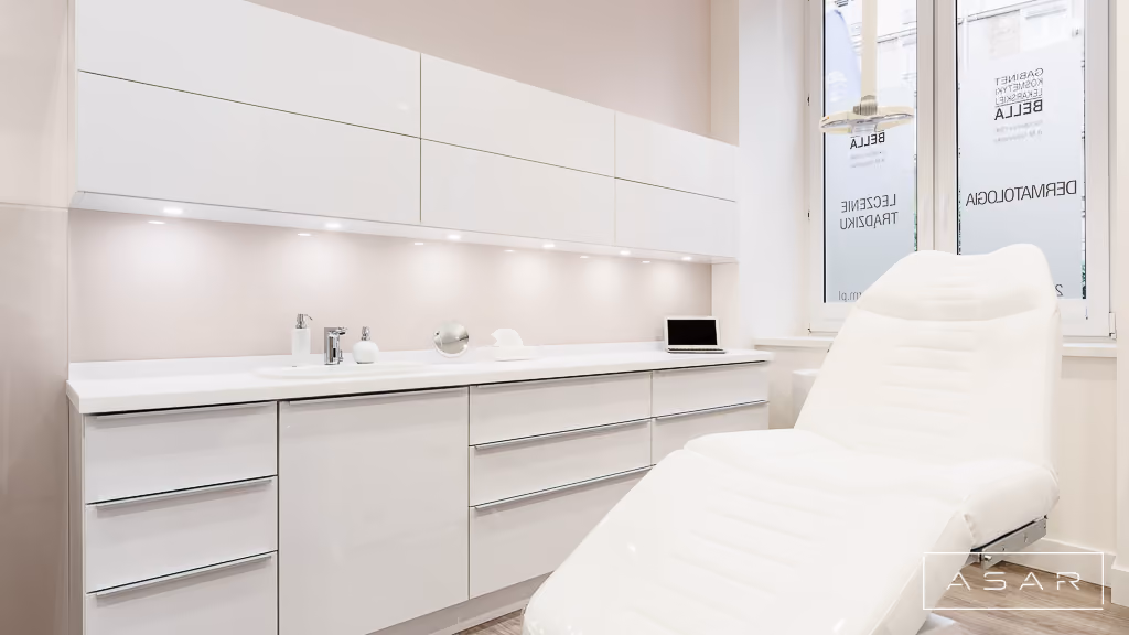 Gabinet zabiegowy Kliniki Bella z białą zabudową meblową, umywalką i fotelem kosmetycznym – ASAR Projekt