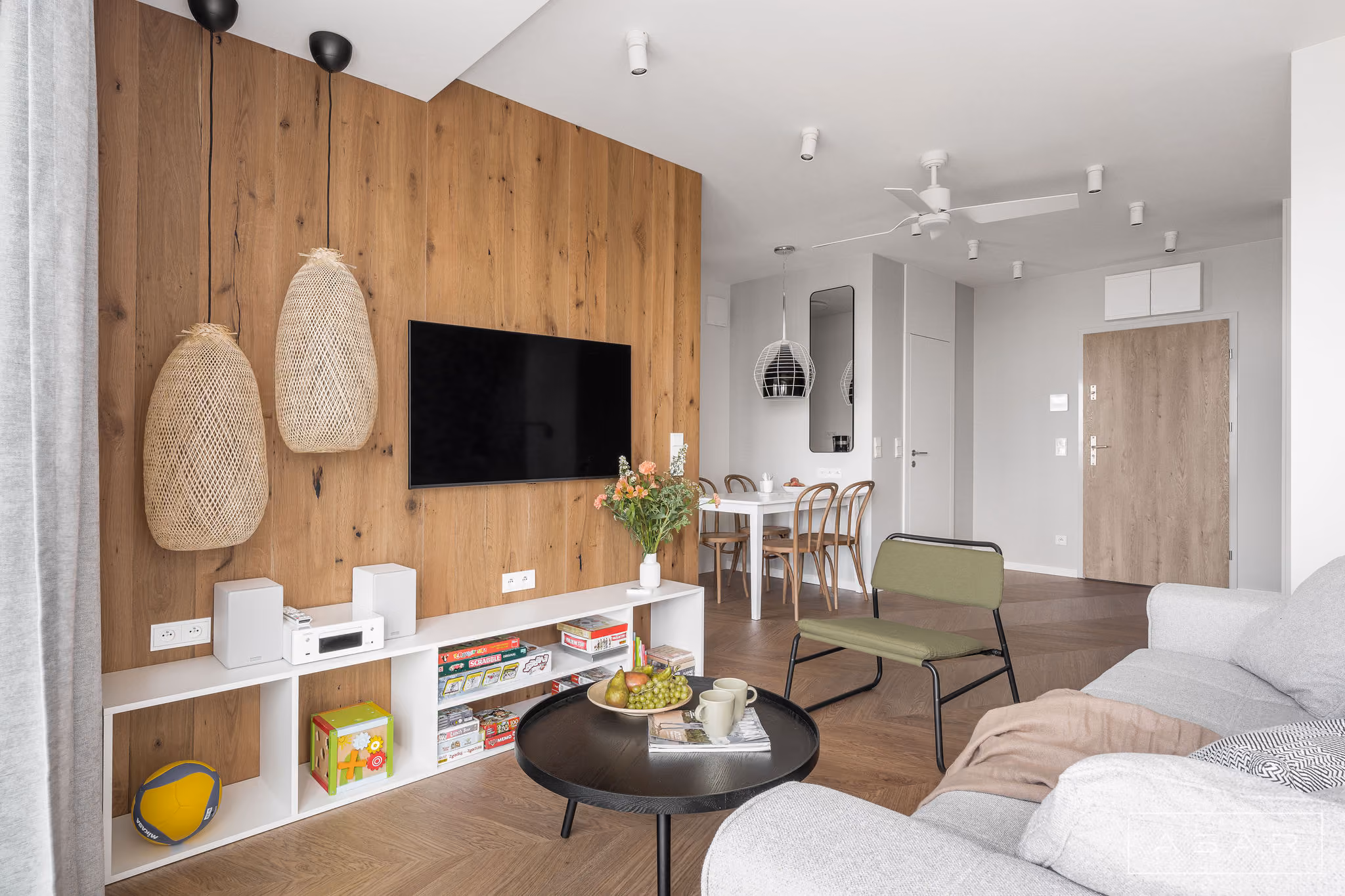 Salon apartamentu nad morzem z drewnianą ścianą, jasną sofą i dużymi przeszkleniami – ASAR Projekt