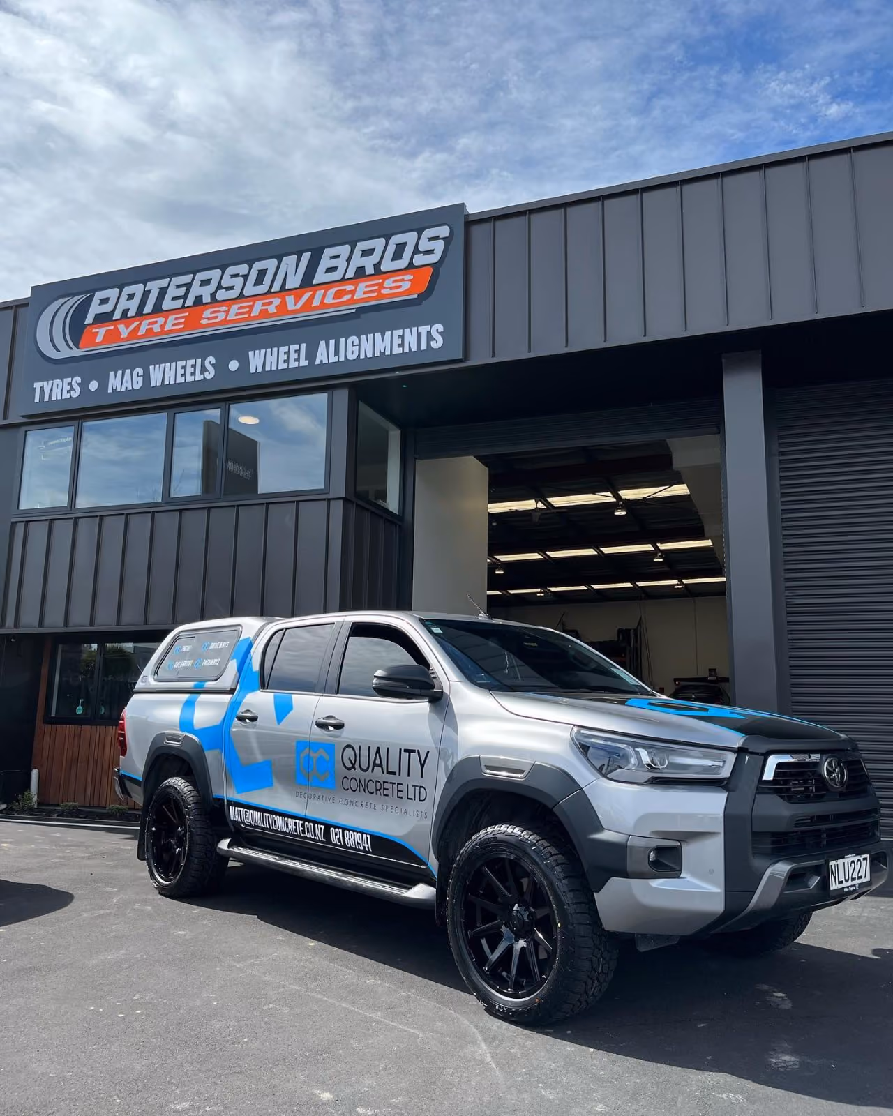 Silver truck with Quality Concrete Ltd logo parked outside Paterson Bros Tyre Services building.