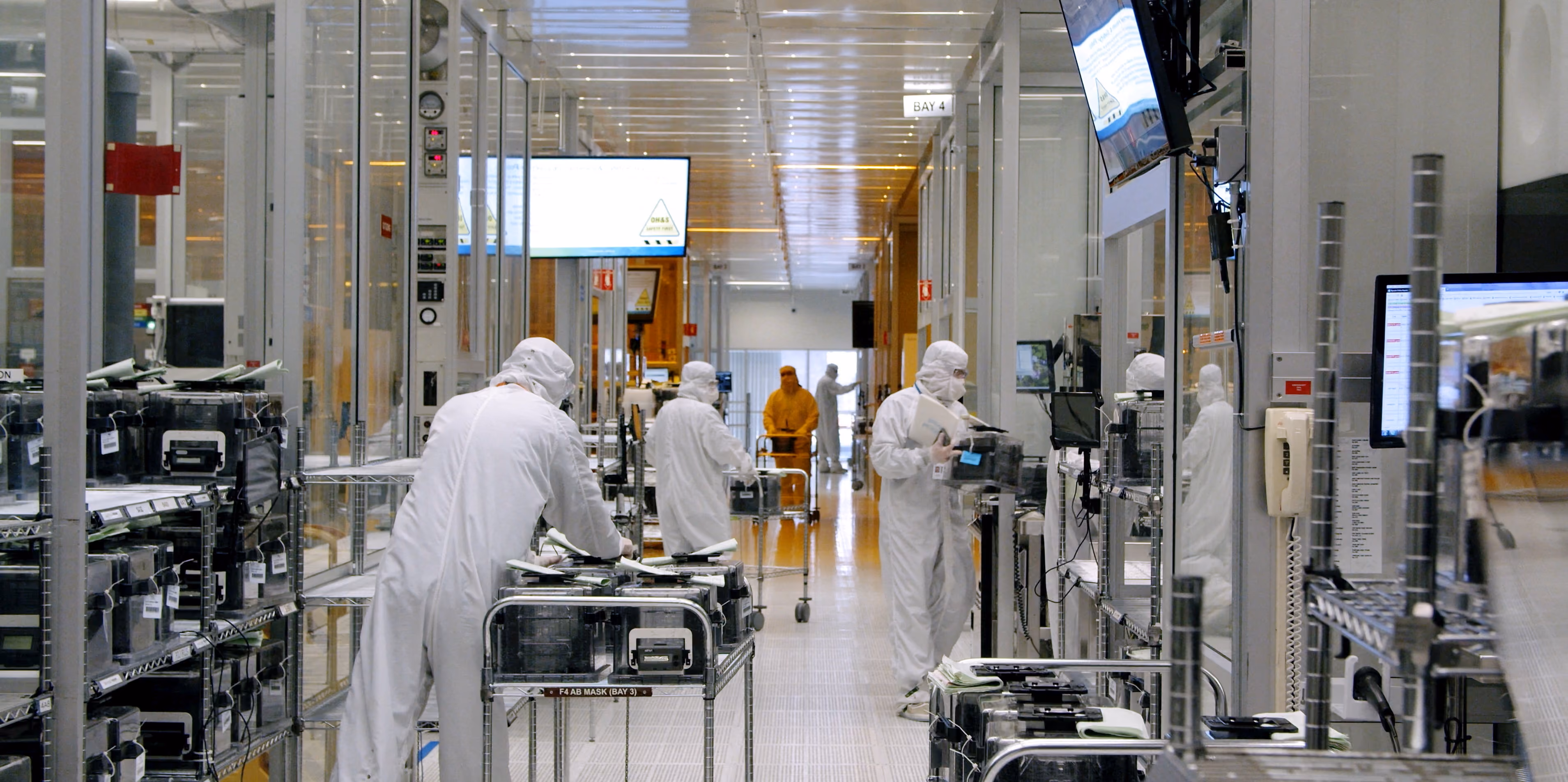 Technicians in cleanroom suits working along a semiconductor wafer fabrication line