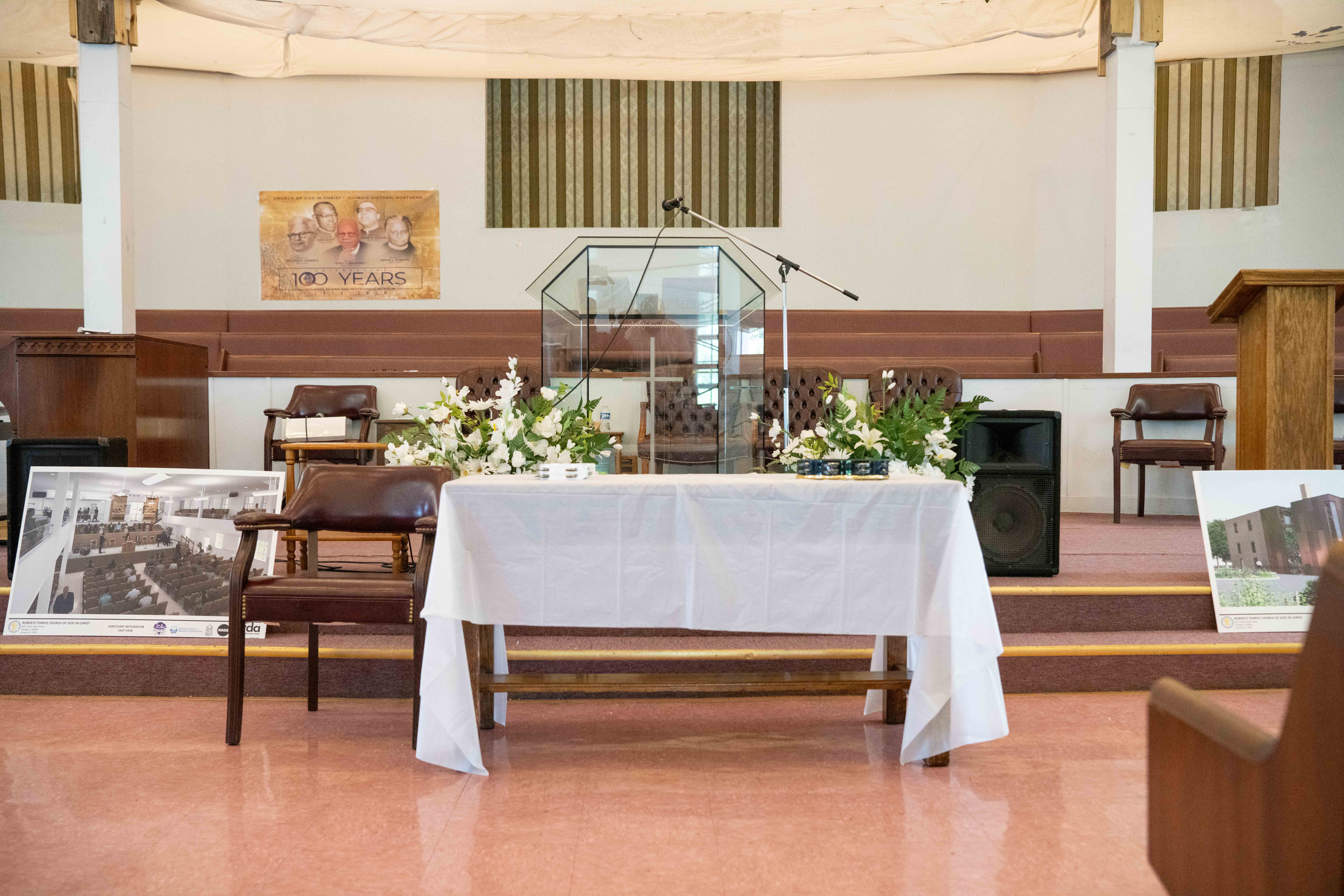 A photograph of the interior of a church. At front is a table draped with a simple white tablecloth.