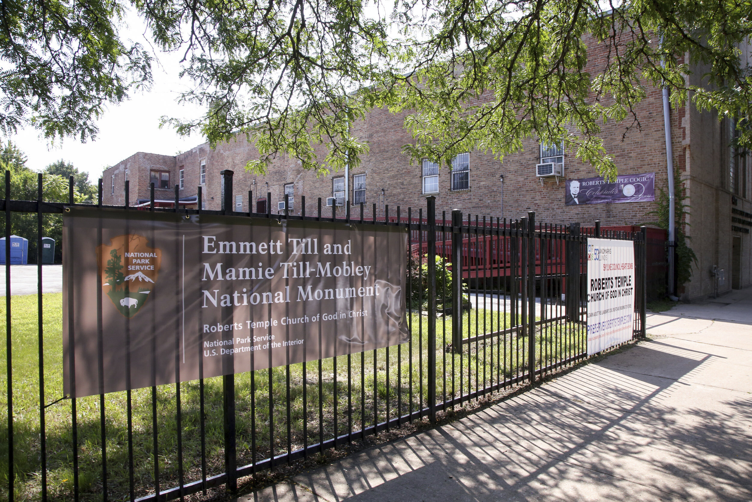 A sign attached to a metal fence announces Roberts Temple as part of the Emmett Till and Mammie Till-Mobley National Monument.