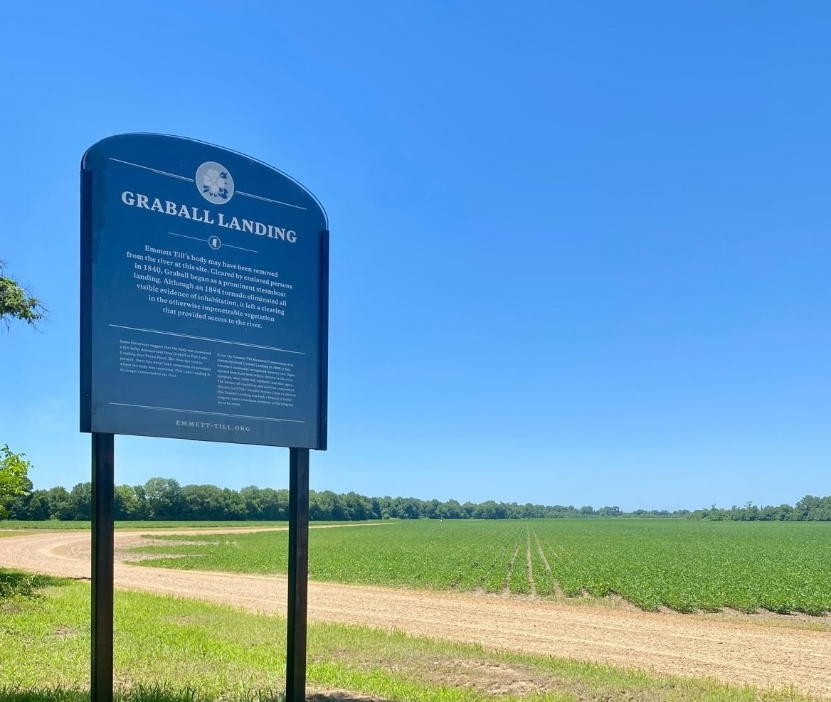 A photograph of a dark green sign marking Graball Landing, where Emmett Till's body was found.