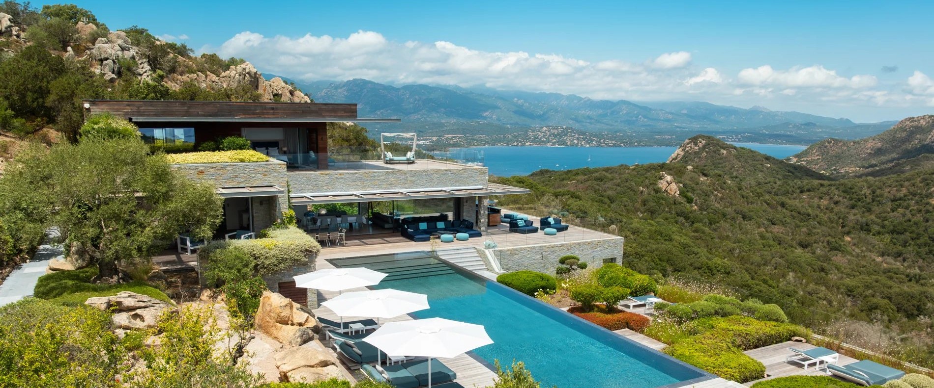 Une villa contemporaine seule dans le maquis corse, sa piscine à débordement et le golfe de Porto-Vecchio en arrière-plan