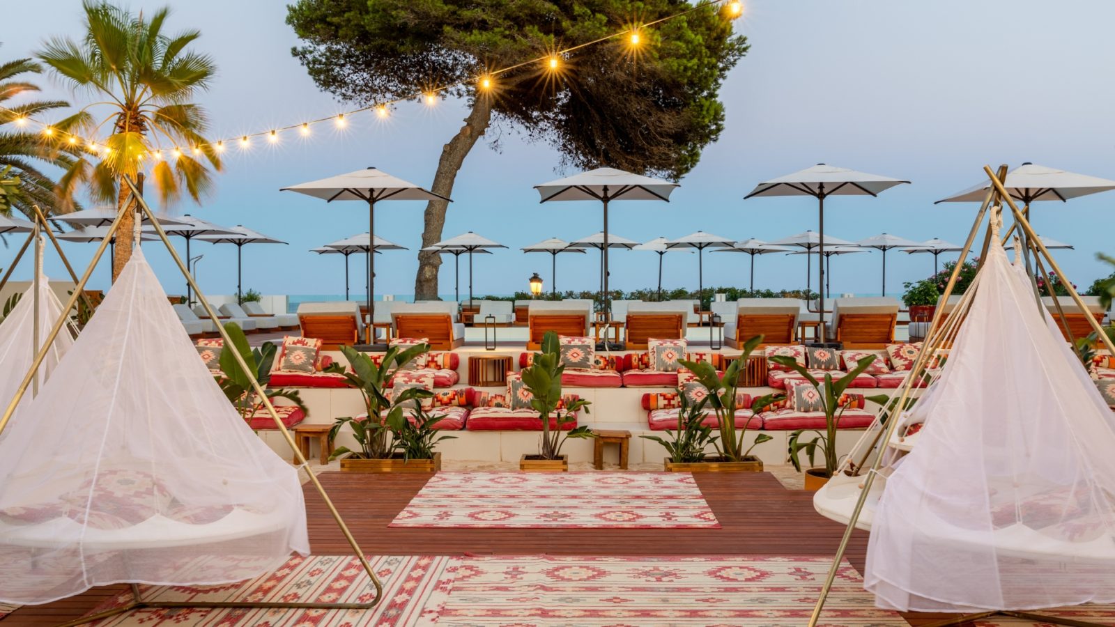 Espace extérieur Tribe du Riomar, avec tapis, petits tipis et guirlandes face à la mer.