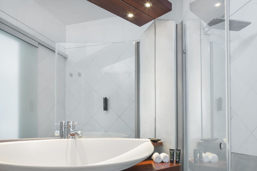 Salle de bains de l'Hacienda Na Xamena avec vasque ovale, miroir et douche vitrée.