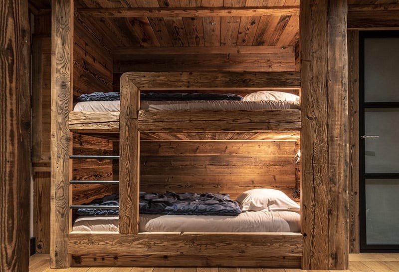 Coin nuit avec deux lits superposés en vieux bois dans une Junior Suite Tradition des Suites Maison Bouvier à Tignes.