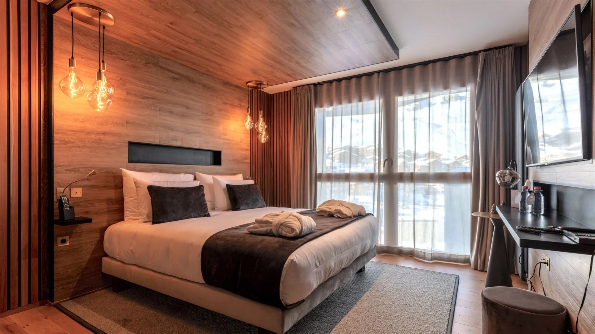 Chambre Supérieure du Diamond Rock à Tignes, avec lit double, mur de bois et grandes fenêtres.