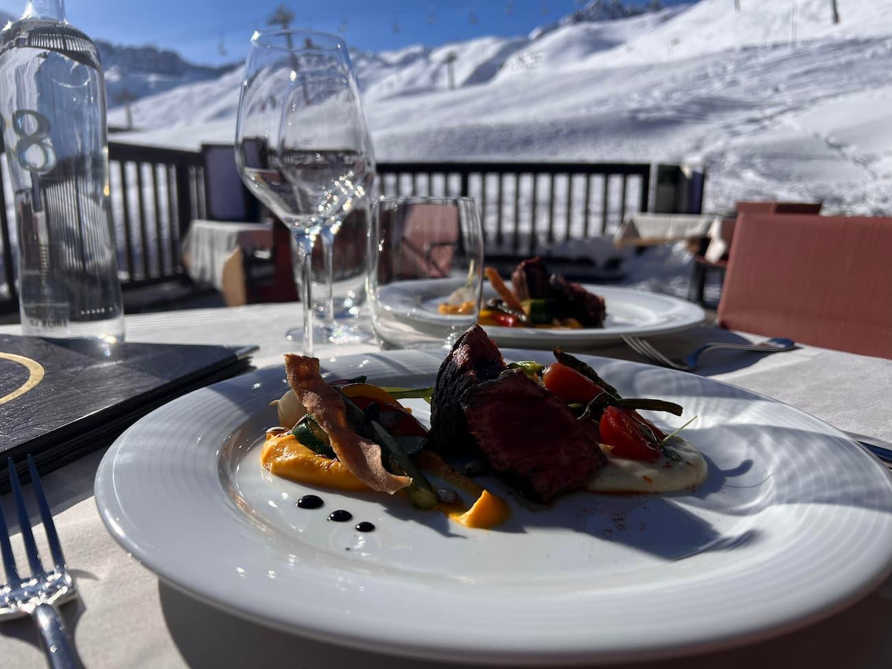 Assiettes du restaurant Le Gourmet des Suites du Montana servies en terrasse face aux pistes enneigées.