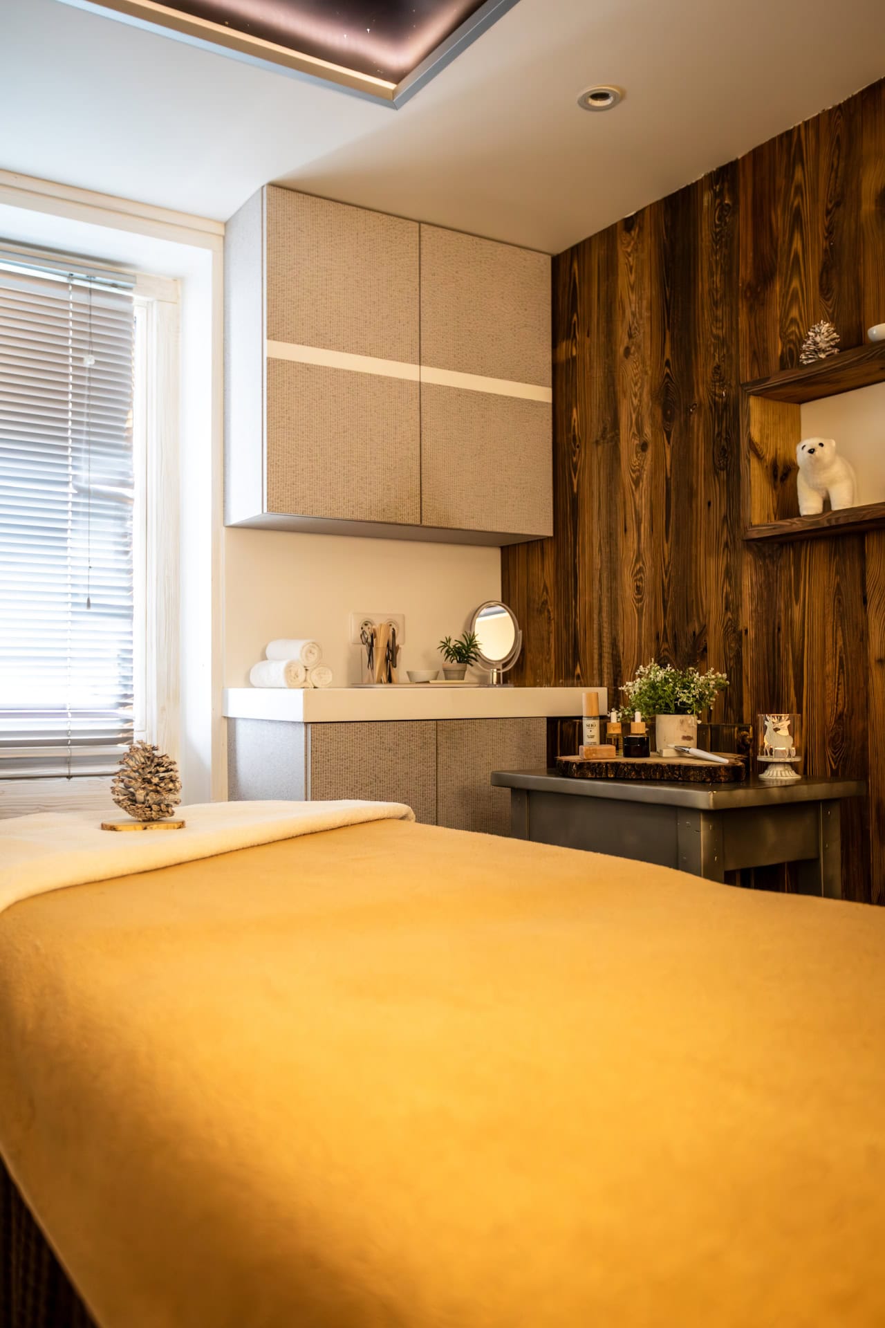 Cabine de massage des Campanules à Tignes, avec table de soins et mobilier de bois.
