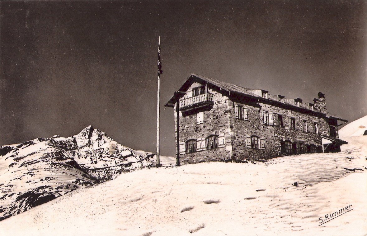 Photographie d’archives en noir et blanc du Refuge, bâtiment de pierre dans un paysage enneigé.