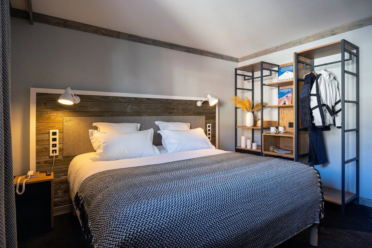 Chambre Confort côté village du Levanna, lit double, tête de lit en bois et penderie ouverte.