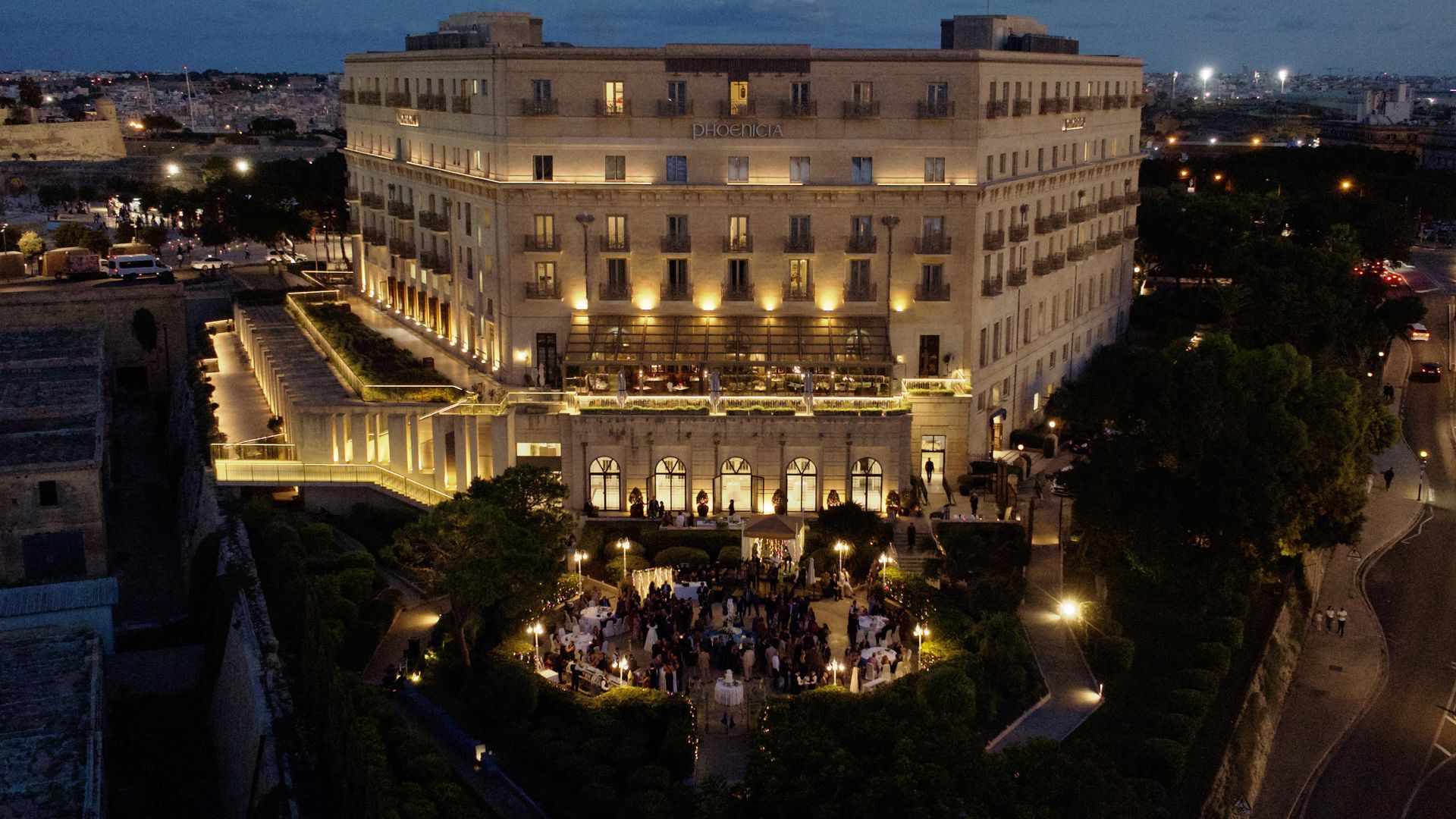 Façade du Phoenicia Malta éclairée à la nuit tombante, devant les jardins de Floriana.