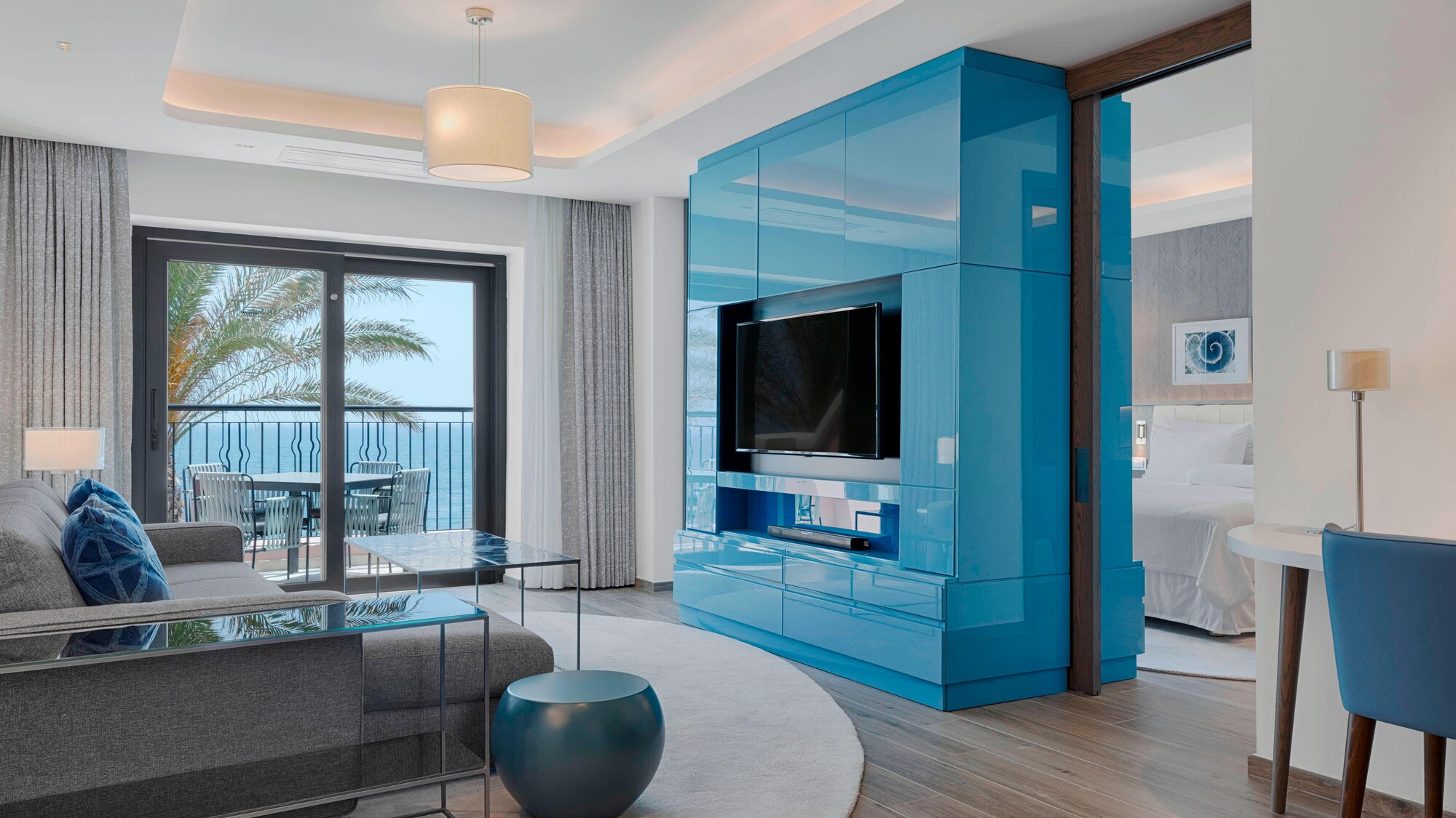 Salon d'une Luxury Bay Suite du Westin Dragonara Resort à Malte, meuble bleu et balcon face à la mer.