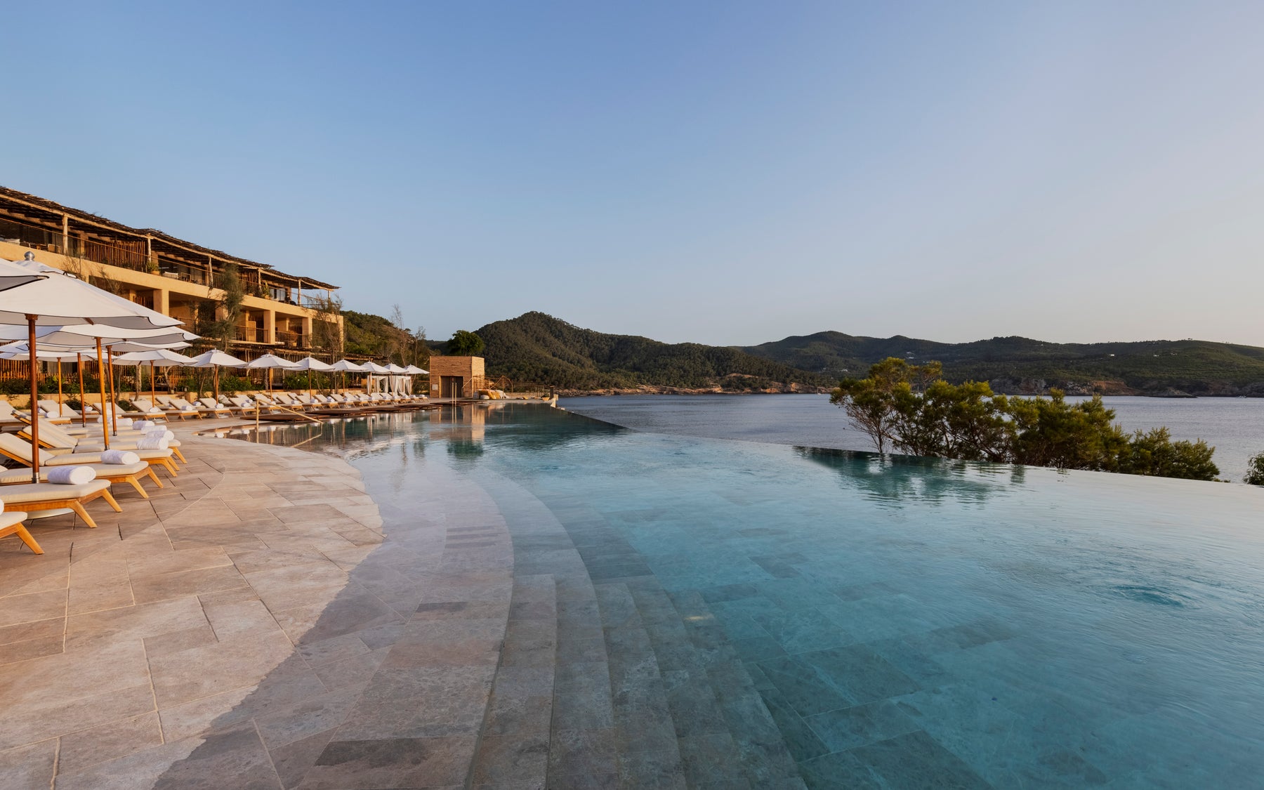 Piscine extérieure du Six Senses Ibiza, avec transats et terrasses face à la baie de Xarraca.