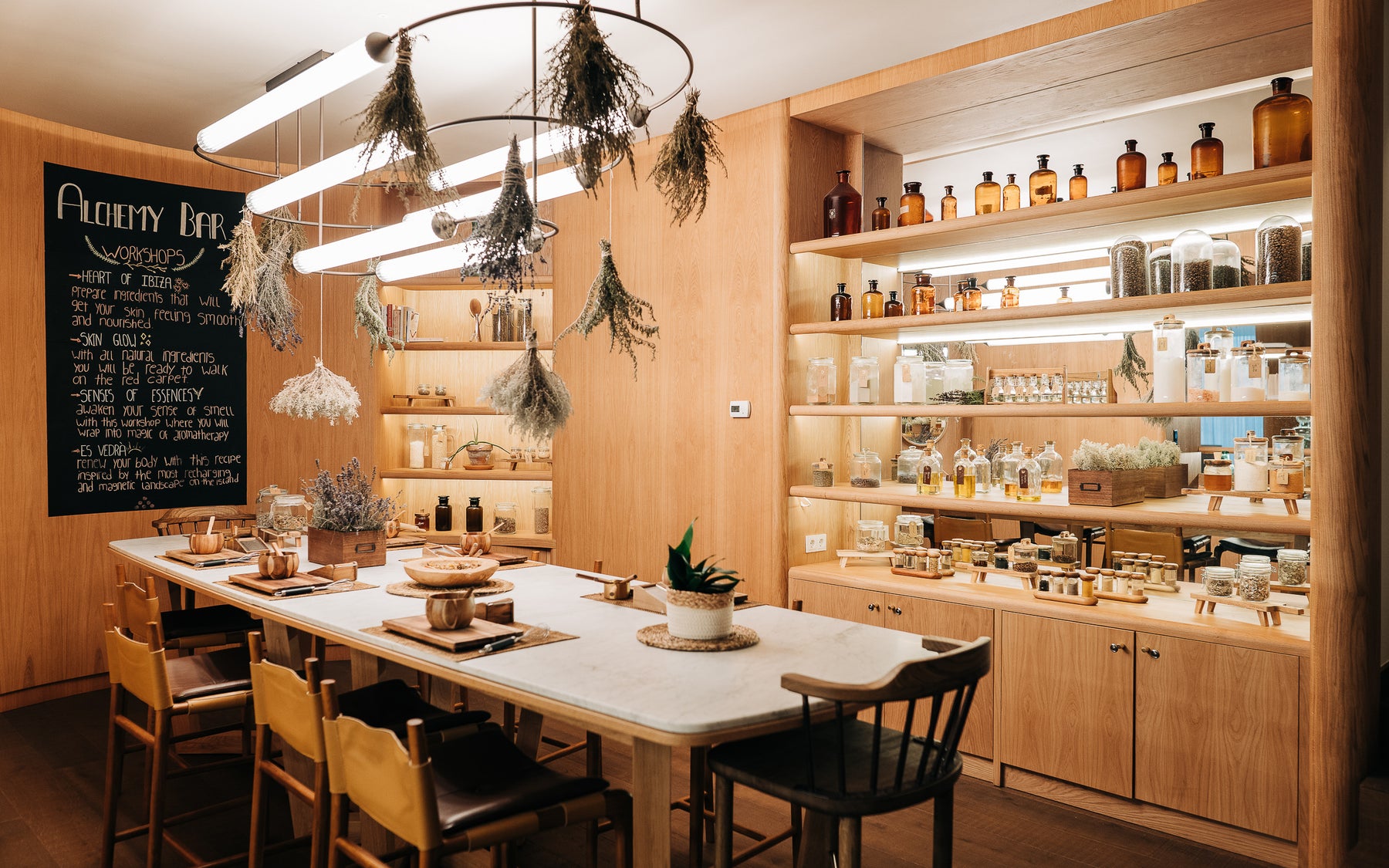 Alchemy Bar du Six Senses Ibiza, table d'atelier, plantes séchées et étagères de flacons.