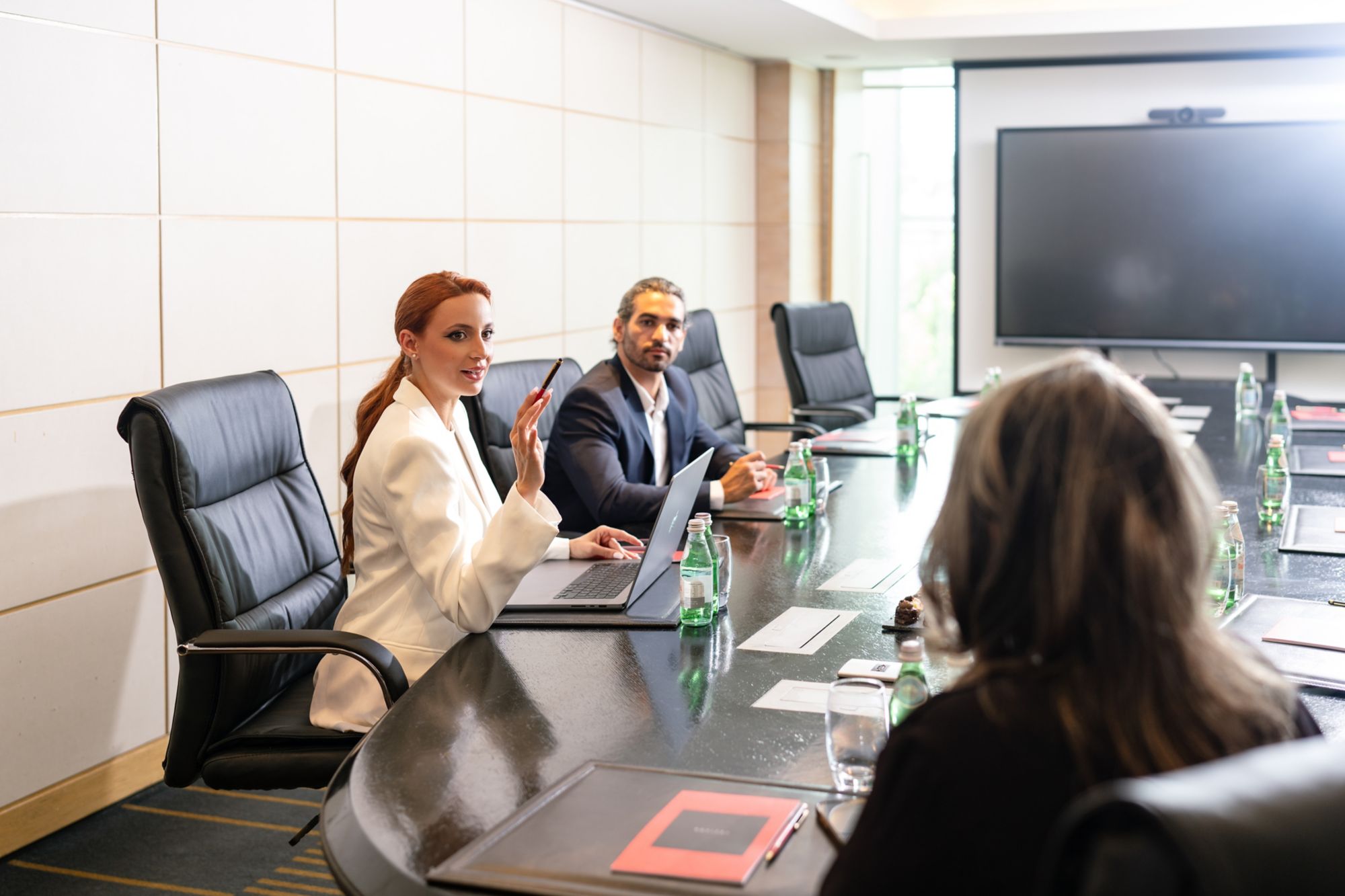 Salle de réunion du Sofitel Casablanca Tour Blanche, avec table, écran et participants près des fenêtres.
