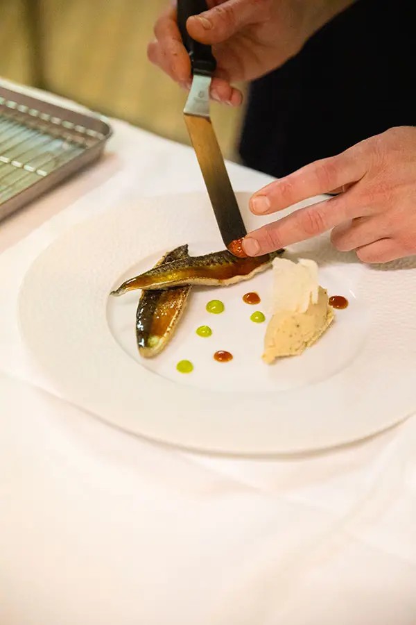 Dressage d'une assiette de poisson au restaurant du Black Bass Hotel à Sévrier.