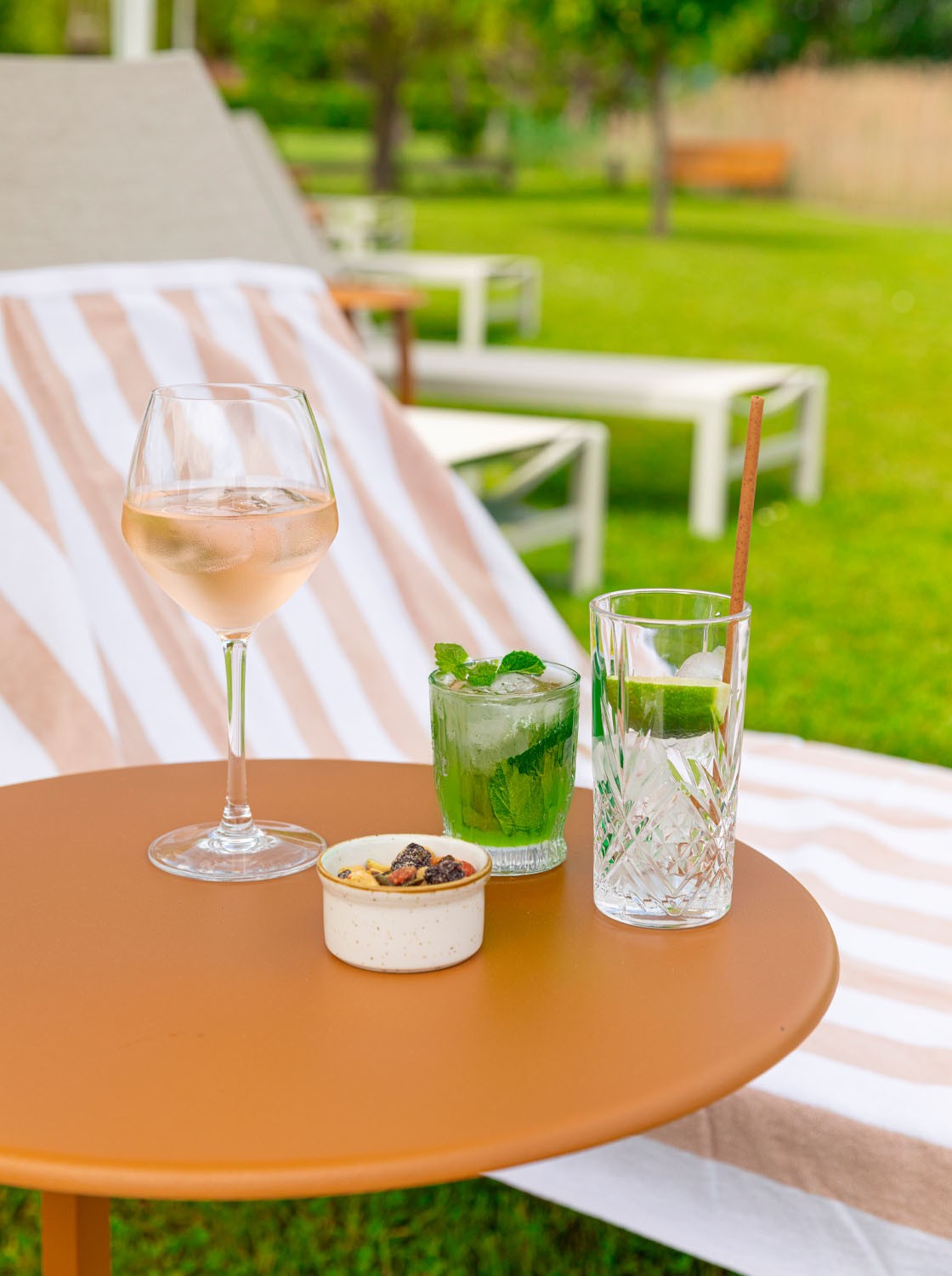Boissons et petite table aux Parasols du Petit Létraz à Duingt, devant les transats du jardin.