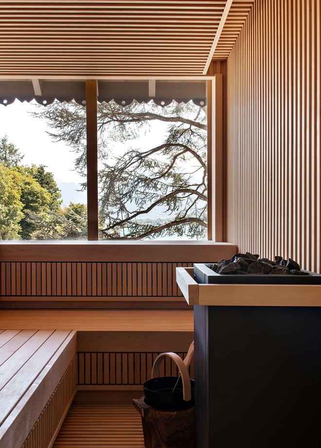 Banquettes et poêle du sauna de l'Auberge du Père Bise, devant une fenêtre ouverte sur les arbres.