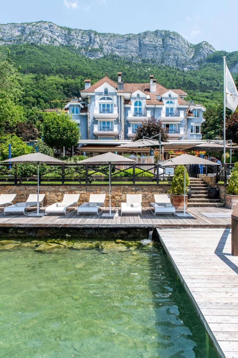 Façade bleue de La Maison Bleue par Yoann Conte, vue depuis le ponton et les chaises longues au bord du lac.