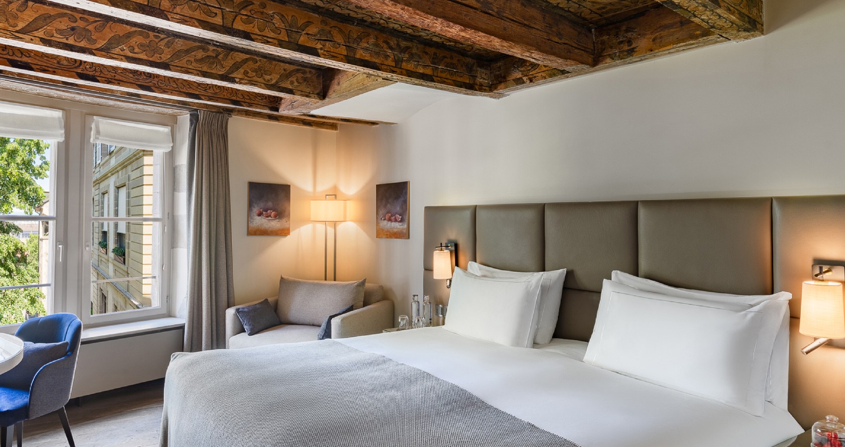 Deux lits sous les poutres dans une chambre de la maison - Hôtel Les Armures, Genève.