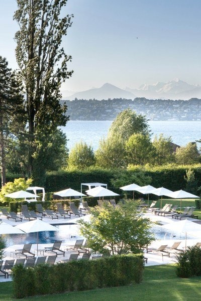 La piscine extérieure, le parc et le lac au second plan - La Réserve Genève, Genève.