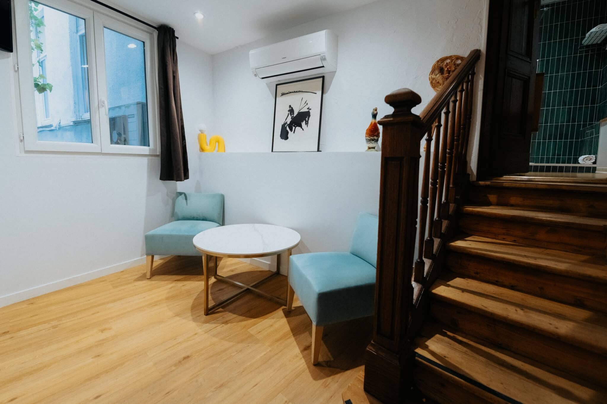 Le boudoir Élisabeth, deux fauteuils turquoise et table ronde au pied de l'escalier de bois, Hôtel Albert 1er à Toulouse