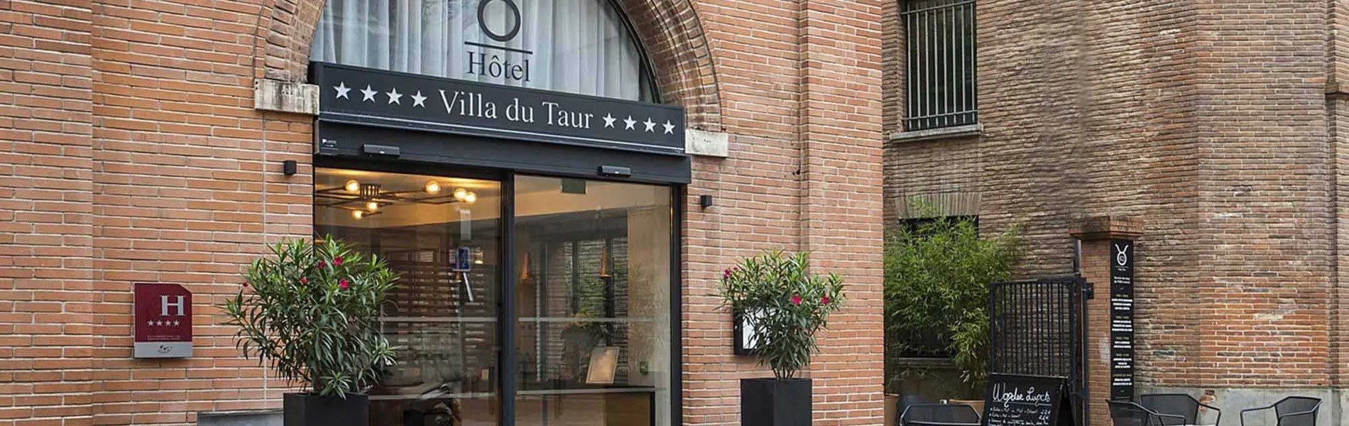 L'entrée de la Villa du Taur sous l'arche de brique, enseigne et bacs de lauriers, rue du Taur à Toulouse