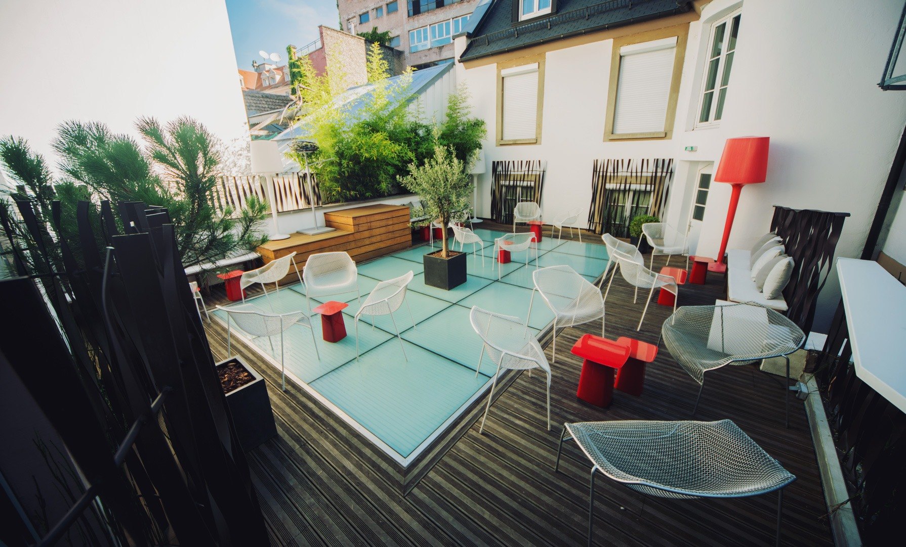 La terrasse en toiture de l'Hôtel Hannong à Strasbourg, fauteuils blancs en résine tressée et oliviers en pot