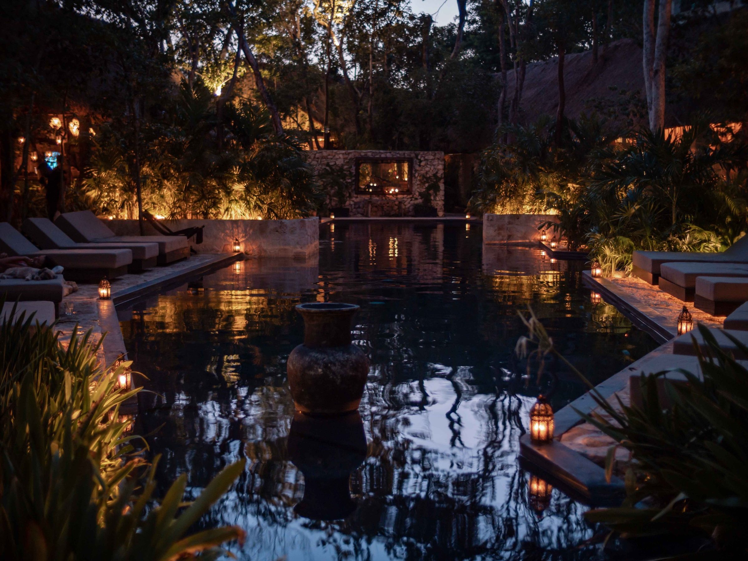 La piscine de l'Hotel Bardo à la tombée de la nuit, bordée de lanternes et de transats, au coeur de la jungle de Tulum