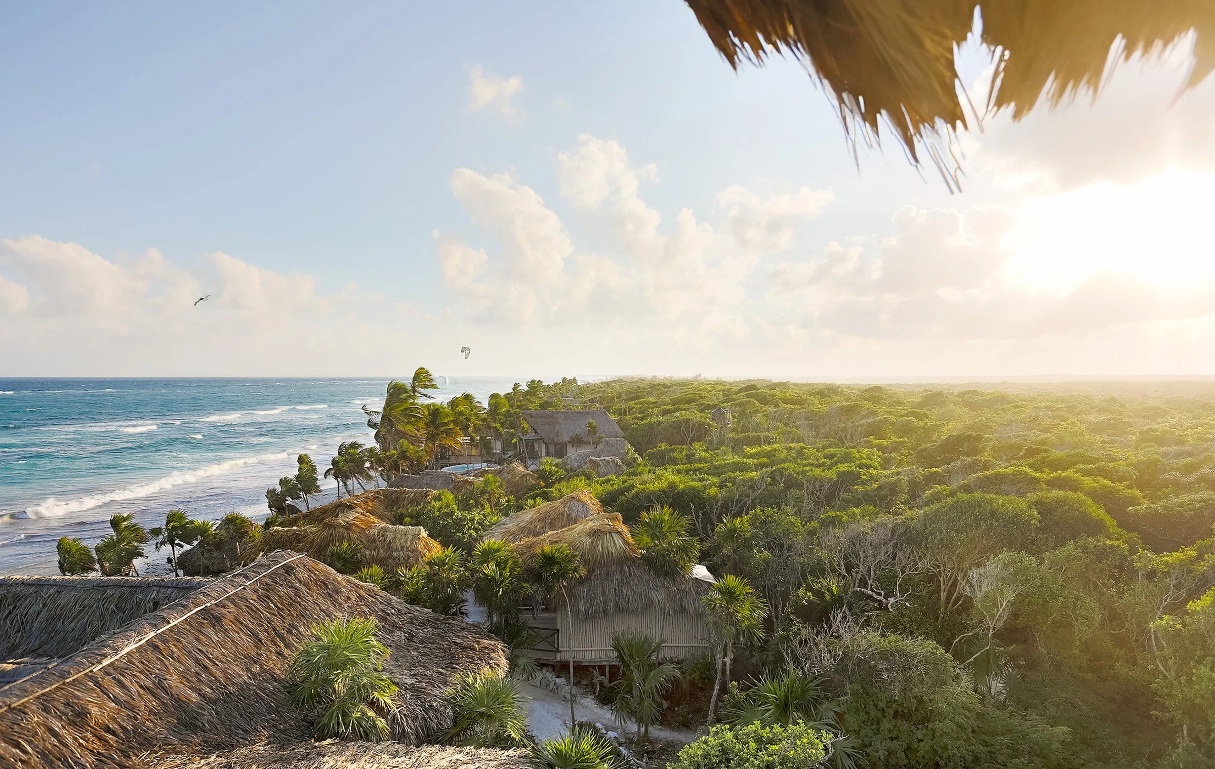 Les toits de palme du Papaya Playa Project entre la jungle et la mer des Caraïbes, au soleil couchant