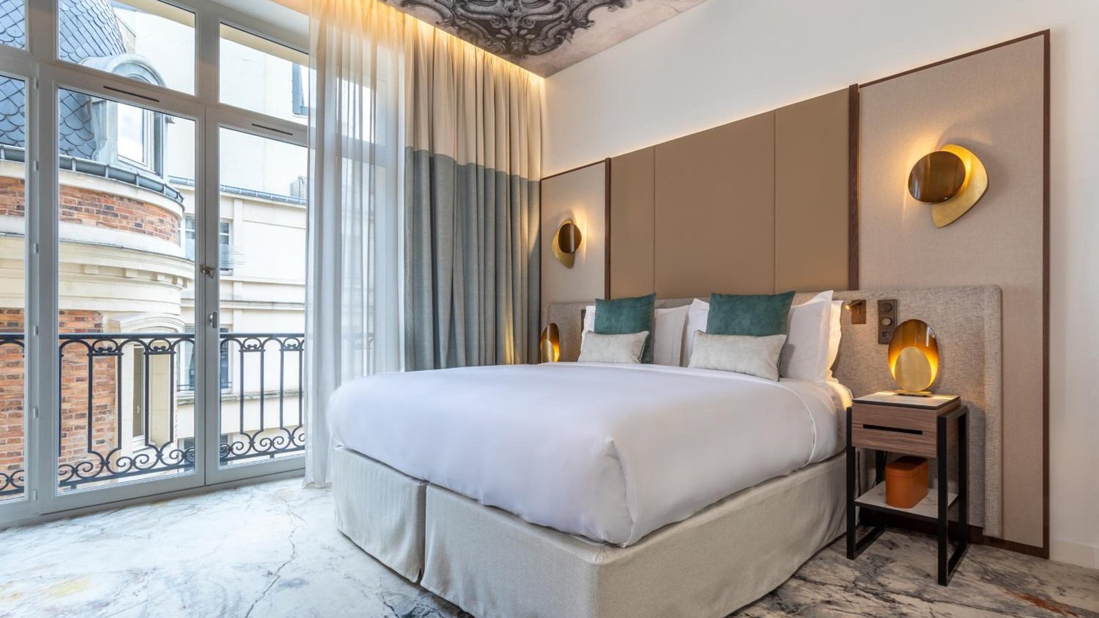 Une Junior King Suite ouvrant sur un balcon, face aux façades haussmanniennes de l'avenue