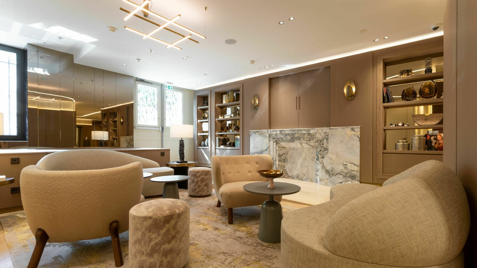 Le lounge de l'hôtel, fauteuils bouclés crème et cheminée de marbre veiné