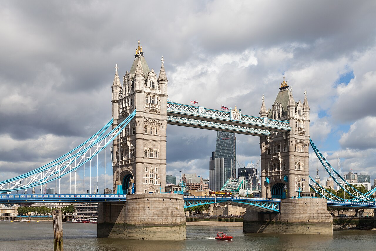 Tower Bridge enjambant la Tamise sous un ciel nuageux, avec les tours de la City en arrière-plan, à Londres