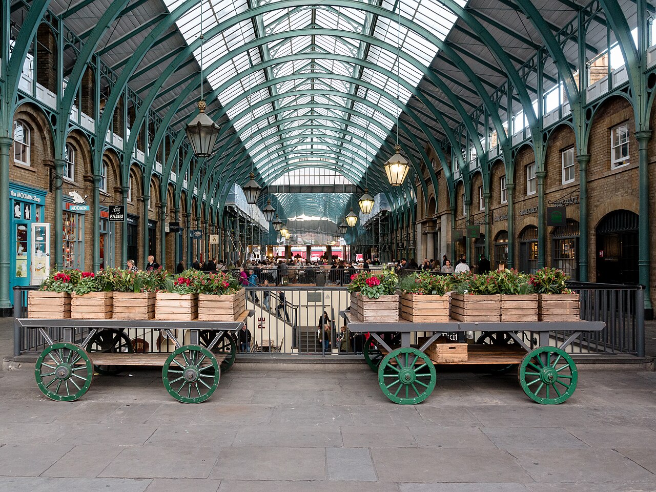 Verrière et arcades de la halle du marché de Covent Garden, avec des charrettes fleuries, à Londres
