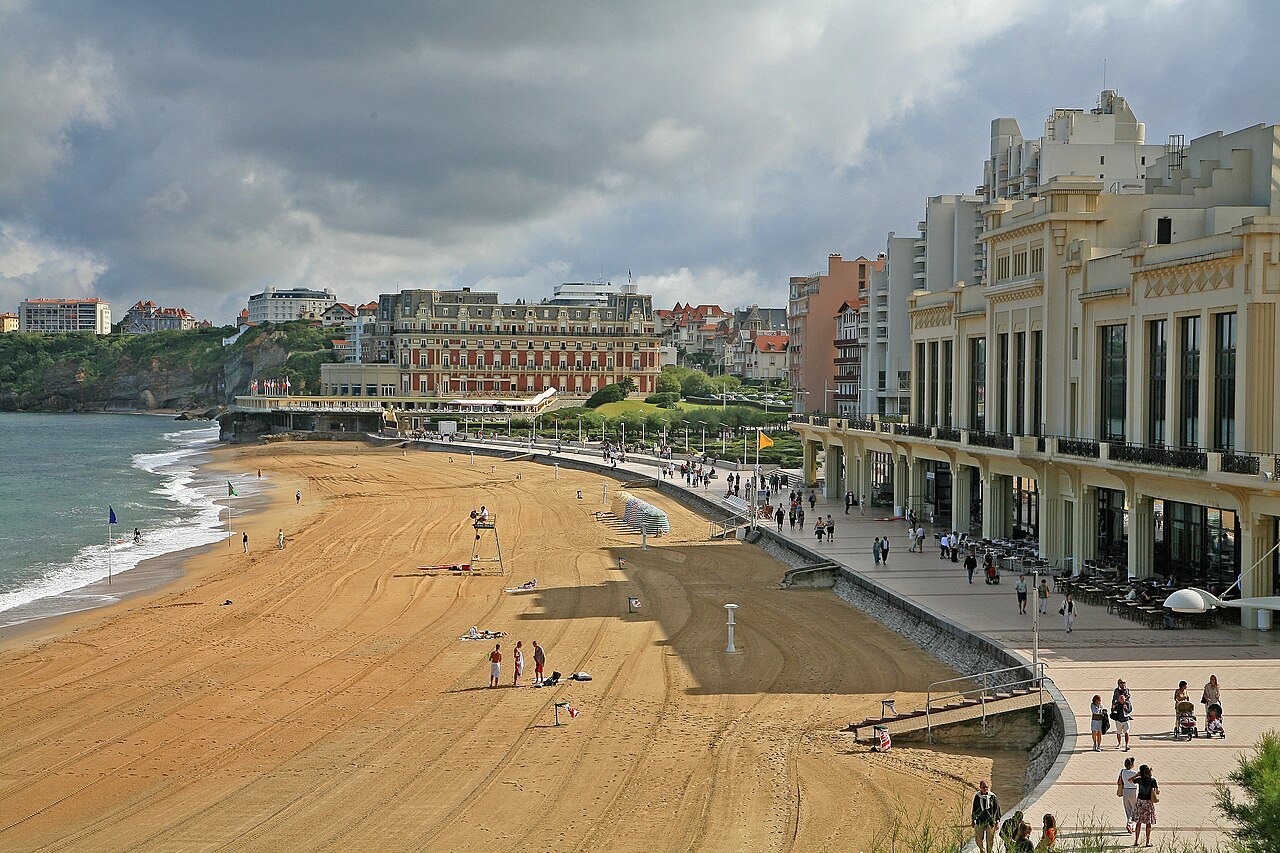 La Grande Plage de Biarritz à marée basse, avec la façade Art déco du casino municipal à droite et l'Hôtel du Palais au fond de la baie