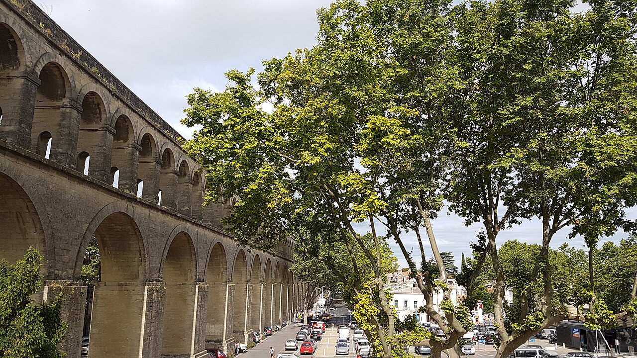 Les deux rangées d'arches de l'aqueduc Saint-Clément vues depuis la rue bordée d'arbres, à Montpellier.
