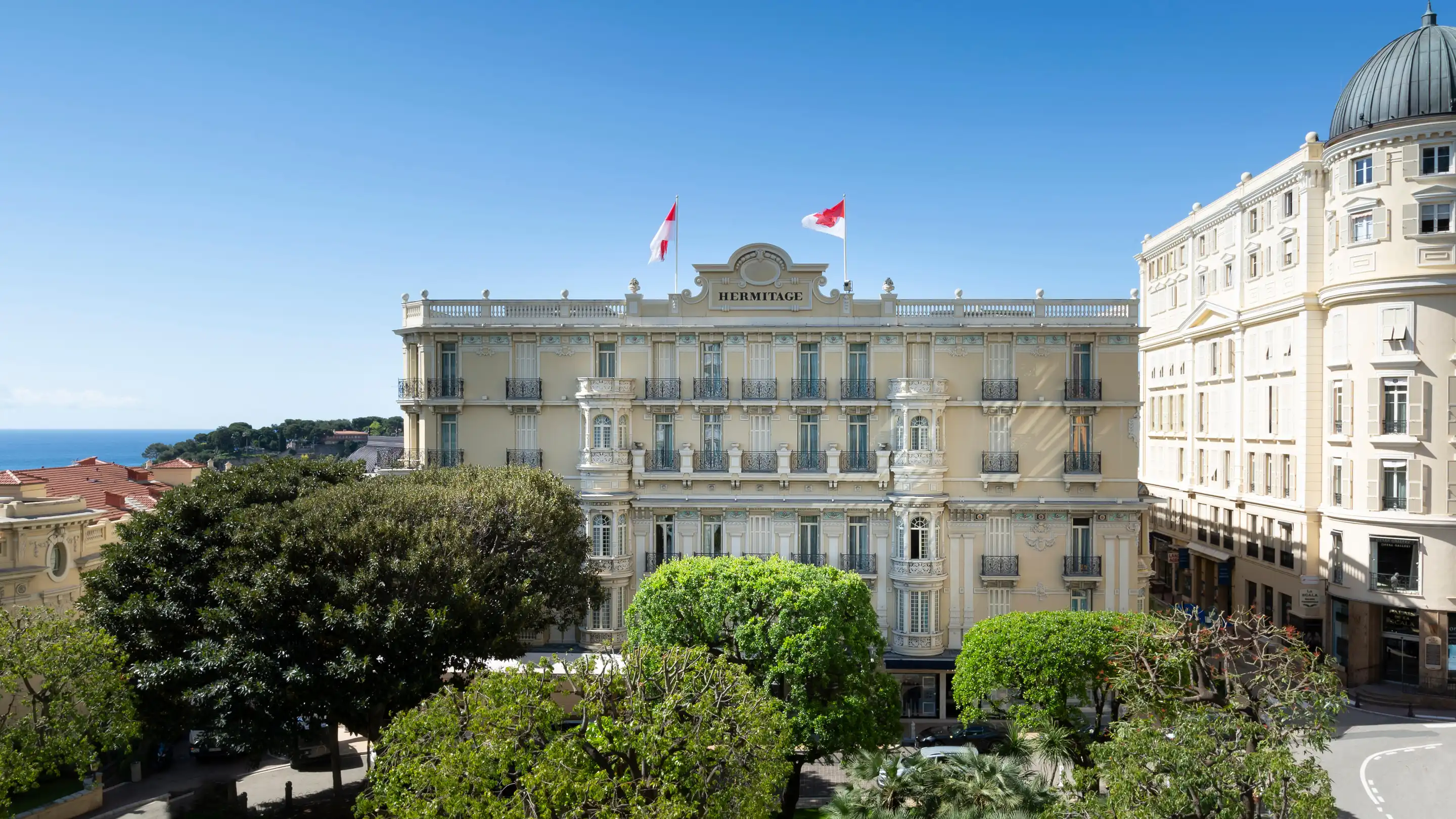 Façade Belle Époque de l'Hôtel Hermitage Monte-Carlo sur le square Beaumarchais à Monaco, drapeaux monégasques au fronton