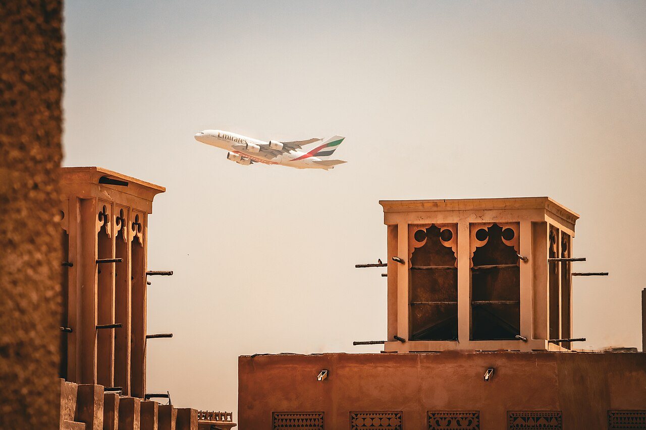 Tours à vent du quartier d'Al Fahidi au soleil couchant, survolées par un Airbus A380 d'Emirates, à Dubaï