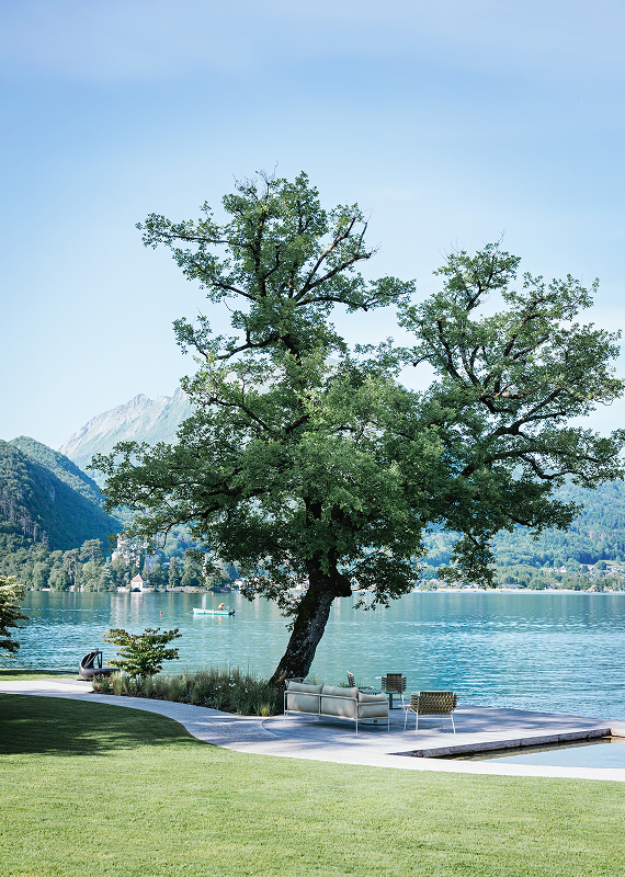 Terrasse sous un grand arbre dans les jardins de l'Auberge du Père Bise à Talloires.