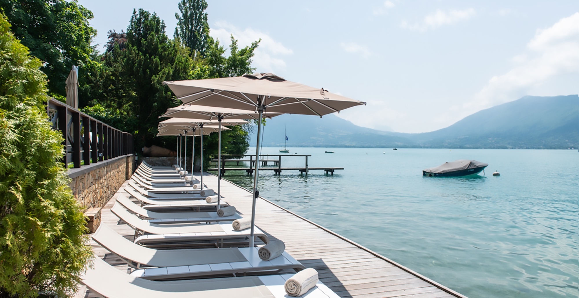 Transats et parasols au bord du lac d'Annecy à La Maison Bleue par Yoann Conte.